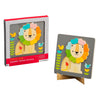 A vibrant wooden lion puzzle by Petit Collage, called the Little Lion Chunky Wood Puzzle, sits on a gray board decorated with flowers and birds, shown beside its branded packaging.