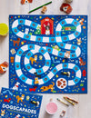 Dogscapades: A Barking Mad Game All About Dogs by Petit Collage is a colorful board game with a winding dog-themed path, dog-shaped tokens, dice, cards, and colored pencils displayed on a light table.