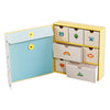 The Petit Collage Baby Memory Box features small pull-out drawers decorated with simple illustrations—bear, tree, rainbow, heart, and owl—paired with a folder secured by a button closure.