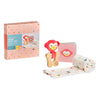 The Petit Collage Little Monkey Baby Gift Set features a pink box, plush monkey rattle, small book with a monkey face cover, and a rolled-up patterned blanket.