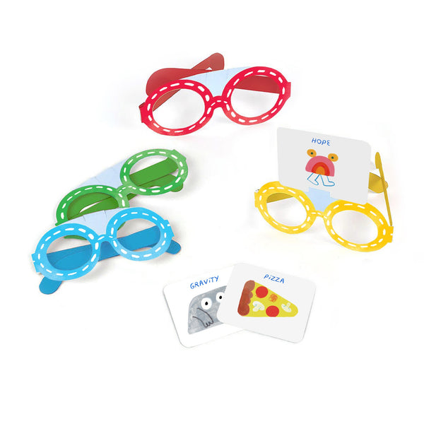 Four colorful paper glasses—red, green, blue, and yellow—from Guessing Things: A What Am I? Game by Petit Collage are displayed. The yellow pair holds a HOPE mushroom card; others show cards labeled “GRAVITY” and “PIZZA.”.