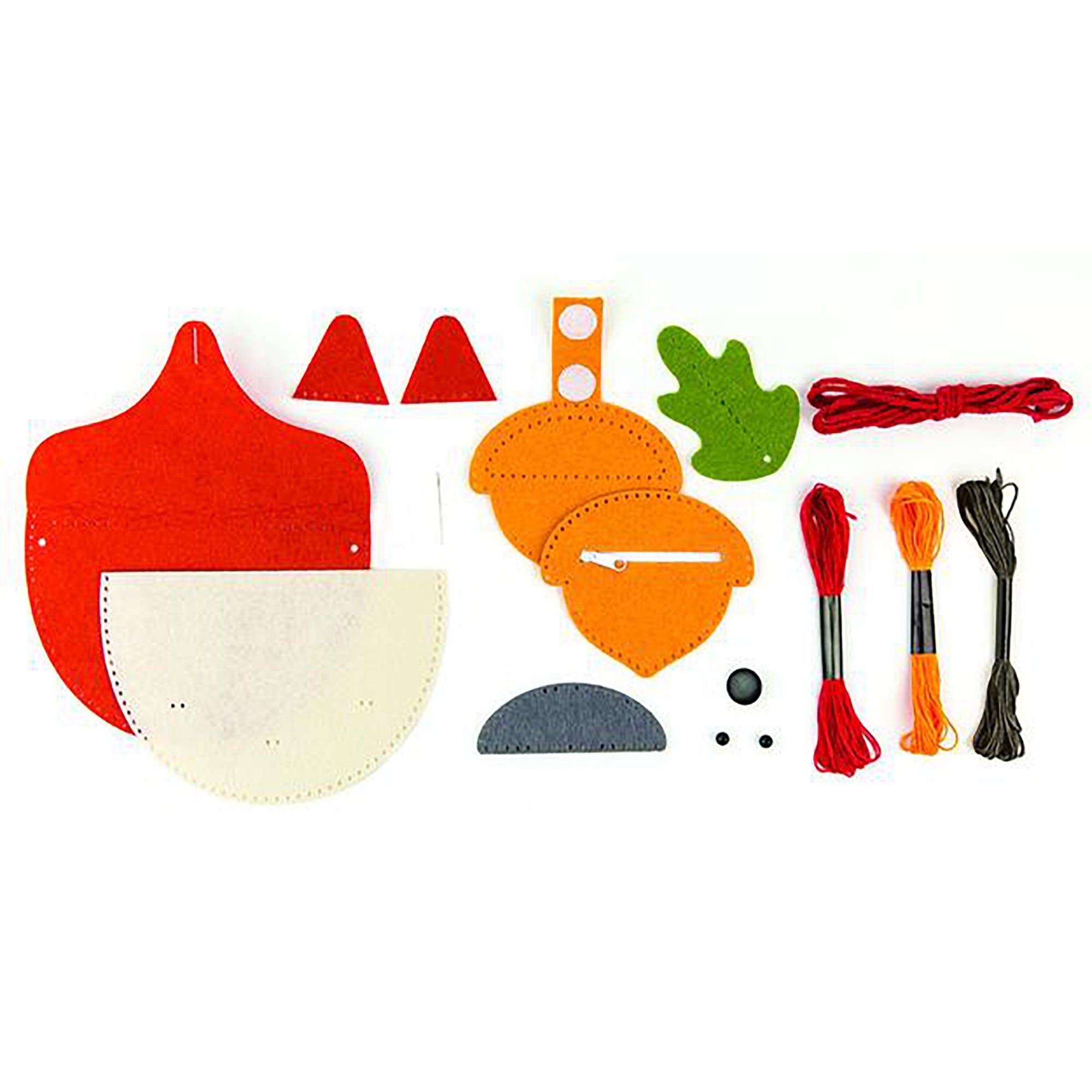 A flat lay of the DIY Woodland Fox Felt Bag craft kit by Petit Collage, featuring colorful felt pieces, embroidery floss, string, buttons, and other materials for a creative project.
