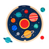 The Petit Collage Multi-Language Solar System Wooden Tray Puzzle shows labeled planets against a starry, dark blue background with orbits.