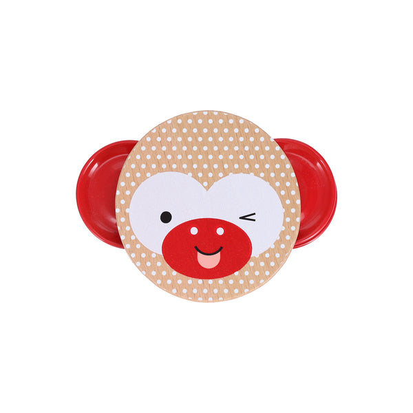 The Petit Collage Shake and Play: Wooden Tambourine is a round, polka-dotted instrument with red side handles, featuring a winking, smiling cartoon monkey face.