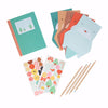 The Petit Collage Festive Pals My Stationery Set includes a notebook, four animal-shaped cards, two festive sticker sheets, and four colored pencils, all arranged on a white background.