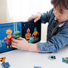 A child uses the Petit Collage Robot Remix Magnetic Play Set to combine robot magnets and create unique robot figures on a magnetic board at a table.