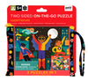 Colorful illustrated packaging for Petit Collage’s Two Sided Superheroes On-the-Go Puzzle for ages 5+, featuring superheroes on both sides and a warning about small parts posing a choking hazard to children under 3.