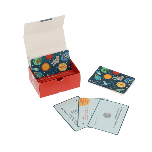Petit Collage Trivia Cards - Space: A red box containing space-themed playing cards, with several cards shown in and on the box and three face-up cards displaying questions and answers.