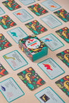 The Dinosaurs Trivia Quiz Cards by Petit Collage are shown with their box surrounded by several dinosaur-themed quiz cards spread out on a wooden surface.