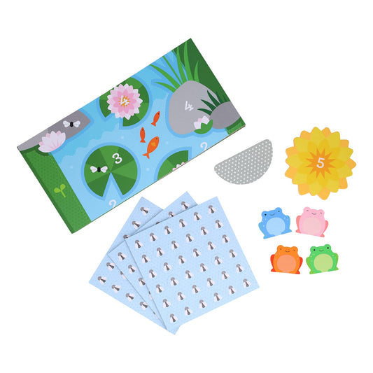 Leaping Frogs! by Petit Collage includes a pond game board, three blue cards, a yellow flower card with the number 5, a gray semi-circle, and four frog tokens in blue, pink, and green.