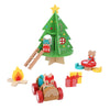 The Petit Collage Christmas Treehouse Wooden Play Set includes a festive treehouse with a ladder, animal figures, campfire, presents, a table with bear, and a car featuring fox and raccoon characters.