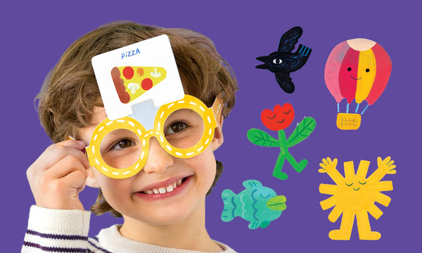 A smiling child wearing oversized yellow glasses plays Guessing Things: A What Am I? Game by Petit Collage, holding a card with a pizza picture on their forehead. Colorful drawings are set against a purple background.