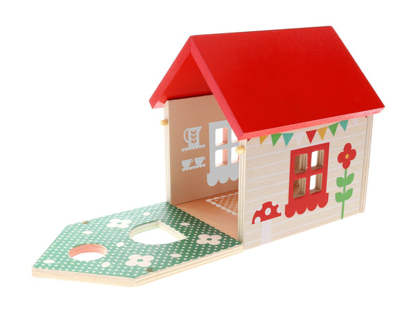 The Mouse House Wooden Play Set by Petit Collage features a wooden toy house with a red roof, painted decorative walls, and a green platform with cut-out shapes.