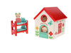 The Petit Collage Mouse House Wooden Play Set features a wooden mouse figure sitting on red bunk beds beside a colorful mouse-themed toy house decorated with flowers and a red roof.
