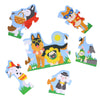 The Petit Collage Shaped Floor Puzzle: Dog Parade features six illustrated jigsaw pieces with cartoon dogs in costumes, displayed on a white background.