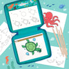 The Petit Collage "How to Draw Ocean Life" kit features step-by-step guides for sketching sea animals like a turtle, octopus, shark, and whale with colored pencils on an ocean-themed blue background.