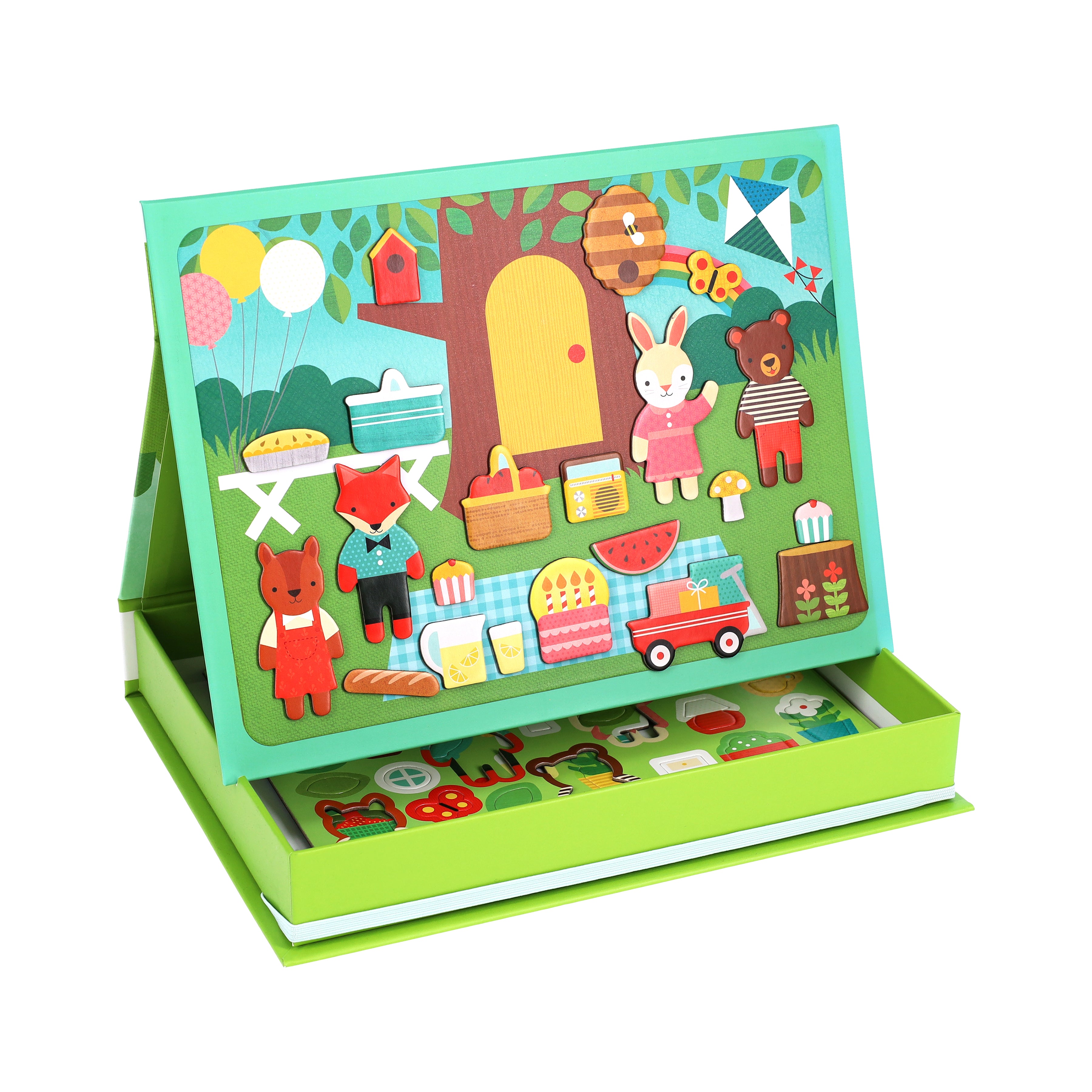 The Petit Collage Treehouse Party Magnetic Play Scene includes animal characters, picnic items, and outdoor scenery that attach to an upright board, plus extra magnetic pieces stored in the box below.