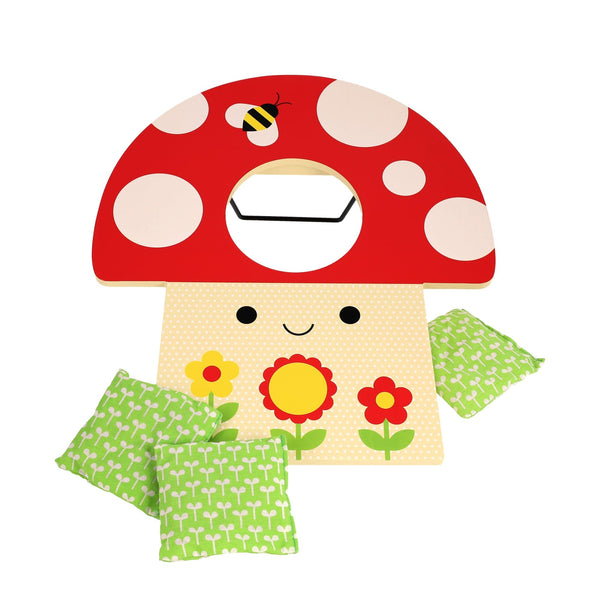The Petit Collage Toadstool Toss Wooden Cornhole Game features a red mushroom top, bee graphic, yellow flower base with a smiling face, and comes with three green patterned bean bags.